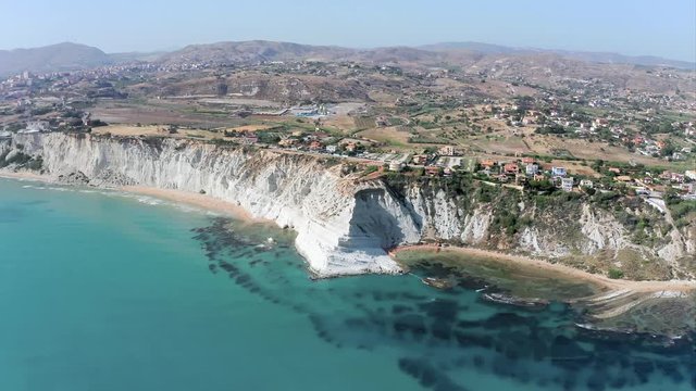 Scala dei Turchi (Stair of the Turks) - natural white marl cliff formation on the south coast of Sicily (Italy), with many people enjoying the sun and turquoise water of mediterranean sea.