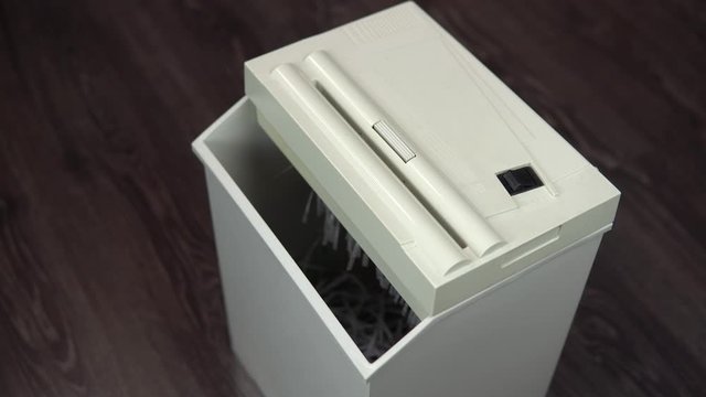 Shredder destroys documents. Businessman in a suit puts a sheet of paper into a paper shredder