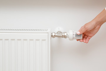 Woman hand adjusting temperature of radiator.