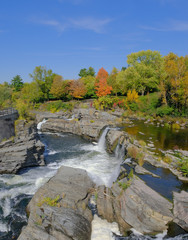 Vibrant orange, yellow, red and green fall colors on trees near waterfall
