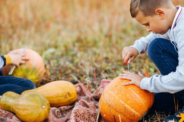 Children playing with pumpkin in autumn Park on Halloween. Boy carving pumpkins