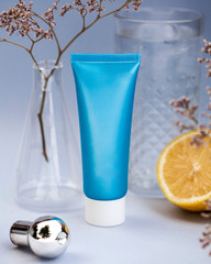 blue cosmetic tube (cream, conditioner or shampoo), in the background a vase and lemon