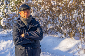 Fototapeta na wymiar Portrait of handsome middle-aged man against beautiful winter landscape. Man walking in snowy forest in sunny frosty day. Human and nature, winter holidays, weekend at countryside concept