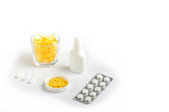 various medicines, yellow capsules, pills of various shapes and colors, spray in the nose on a white background with place for text