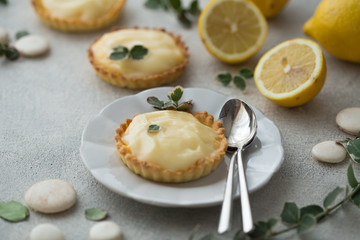 Lemon curd tart served with green leaves and lemon. Tartalets, lemon curd tarts
