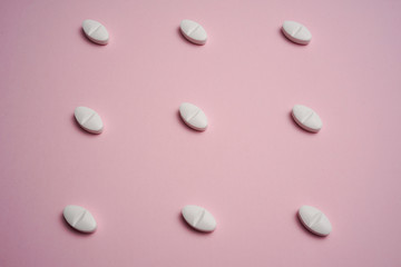 White pills on pink background
