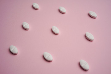 White pills on pink background