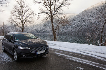 black car sedan on a background of a mountain lake in winter
