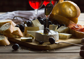Assorted cheeses on wooden board. Camembert, cheese with blue mildew, gouda, hard cheese,...