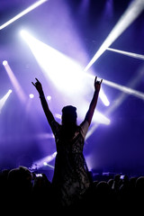 Silhouette of girl with raised hands enjoys the concert
