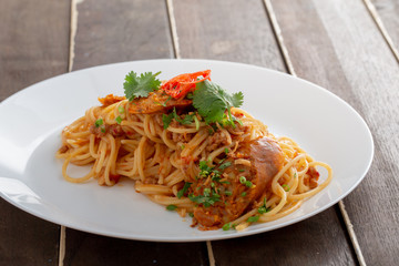 Spicy Spaghetti with Thai sausage on wood table.