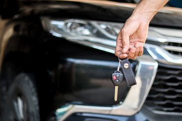 A man holding car key on black car background, journey of life concept