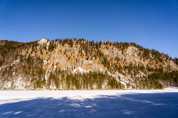 Fototapeta na wymiar huge hill with a frozen lake in the foreground and blue sky in the background. Austrian winter landscape photography