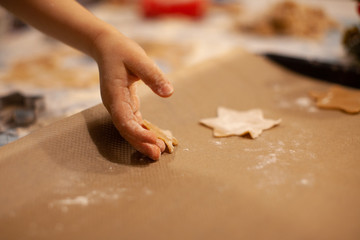 children's hands put gingerbread cookies in the shape of a star on the kitchen baking sheet on New Year's Eve