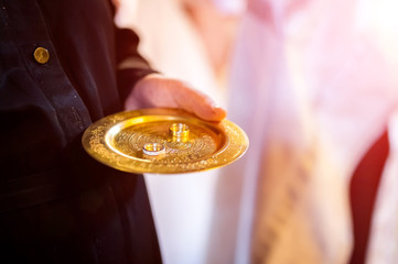 Gold wedding rings on the golden plate in the church