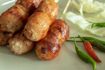 Grilled sausages on skewers with peppers on a white plate