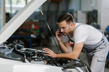 Auto mechanic talking on mobile phone in auto repair shop