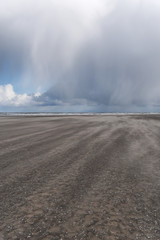 Wetterwechsel am Strand mit Wind, Regen und dunkle Wolken am Kijkduin Strand bei Den Haag, Holland, Niederlande