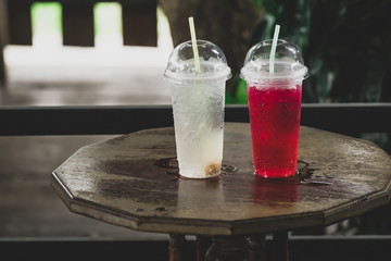  Sweet and cold red and white drinks in a plastic glass with a tube for sucking water. Put on a wooden table in a coffee shop