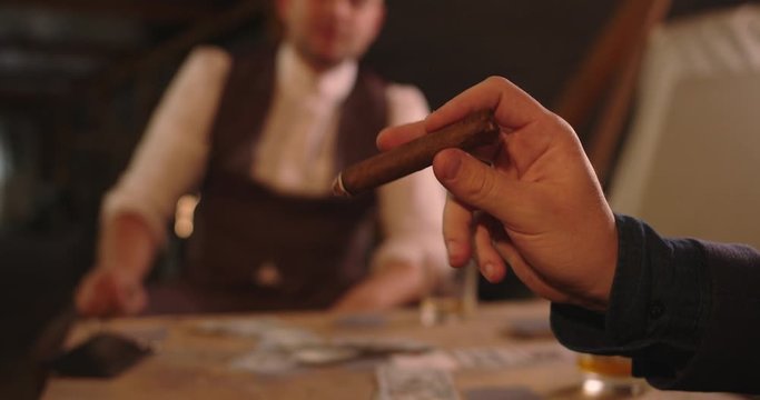 Mans hand shakes off the ashes of cigar