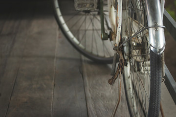 The ancient bike was parked on the wooden floor. The stand had rust.