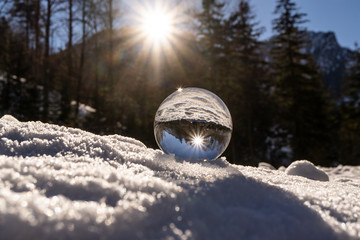 lens ball during winter in austria europa, crystal ball in the snow with an amazing sunset in the...