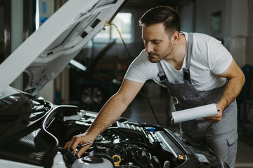 Fototapeta na wymiar Young mechanic going through checklist in auto repair shop