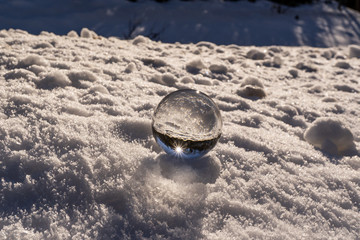 lens ball during winter in austria europa, crystal ball in the snow with an amazing sunset in the background