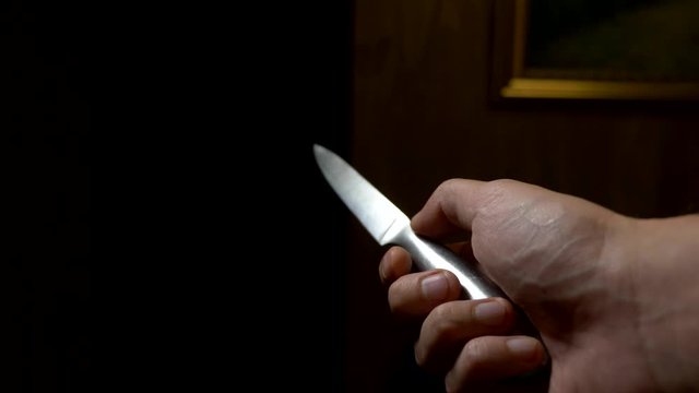 concept of halloween, violence. first-person view. male hand with a knife moves along a dark corridor