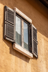 The wooden windows have glass on the inside with the plaster walls of a vintage house.