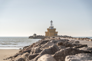 Fototapeta na wymiar beautiful old lighthouse on the coast of Venice Italy Europe. Lighthouse on the beach with rocks and the ocean in the background