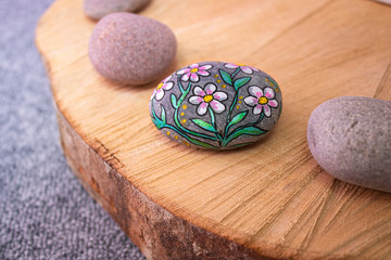 DIY Do it yourself - Autumn is craft time. Self-painted stone with colorful flower pattern arranged on a wooden plate