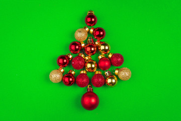 Christmas tree made with small baubles on green background