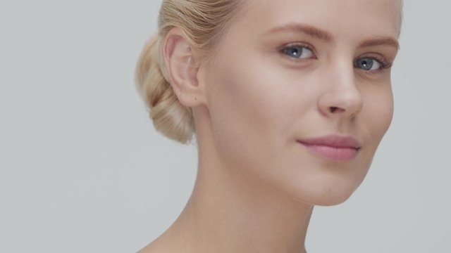 Studio portrait of young, beautiful and natural blond woman applying skin care cream. Face lifting, cosmetics and make-up.
