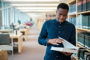 Young black man choosing book in public library