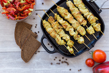 chicken skewers in a pan with pepper salad and tomato and spices