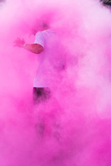 une personne courant dans une fumée colorée rose. Holi. Une silhouette dans une brume colorée