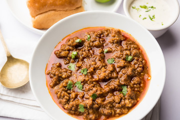 Kheema / keema Pav or Khima Paav is a spicy curry dish made up of minced chicken or lamb cooked with onion, tomatoes, served with buns. selective focus