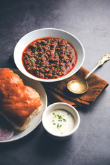 Kheema / keema Pav or Khima Paav is a spicy curry dish made up of minced chicken or lamb cooked with onion, tomatoes, served with buns. selective focus