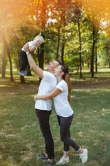 Happy parents play in the park with their child.