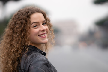 Happy young woman with curly hair walking around the streets of Rome, Italy