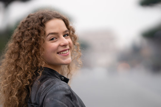 Fototapeta Happy young woman with curly hair walking around the streets of Rome, Italy