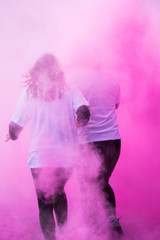 des personnes courent dans une fumée colorée rose holi