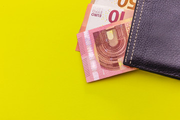 Black leather Men's Wallet with Euro cash on yellow background. Place for text