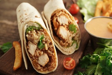Burritos Wrap with grilled chicken rice and veggies on wooden background, selective focus