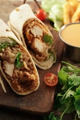 Burritos Wrap with grilled chicken rice and veggies on wooden background, selective focus