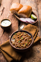 Kheema / keema Pav or Khima Paav is a spicy curry dish made up of minced chicken or lamb cooked with onion, tomatoes, served with buns. selective focus