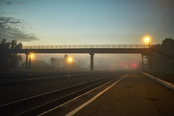 Fototapeta na wymiar night railway is lit by yellow lanterns in the fog