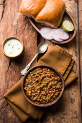 Kheema / keema Pav or Khima Paav is a spicy curry dish made up of minced chicken or lamb cooked with onion, tomatoes, served with buns. selective focus