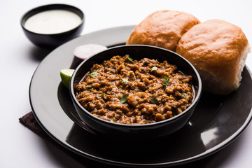 Kheema / keema Pav or Khima Paav is a spicy curry dish made up of minced chicken or lamb cooked with onion, tomatoes, served with buns. selective focus